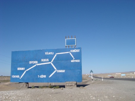 Blaues Straßenschild in Karakalpakstan, Usbekistan, mit Streckenkarte zwischen Nukus, Kungrad, Moynaq und Beruniy